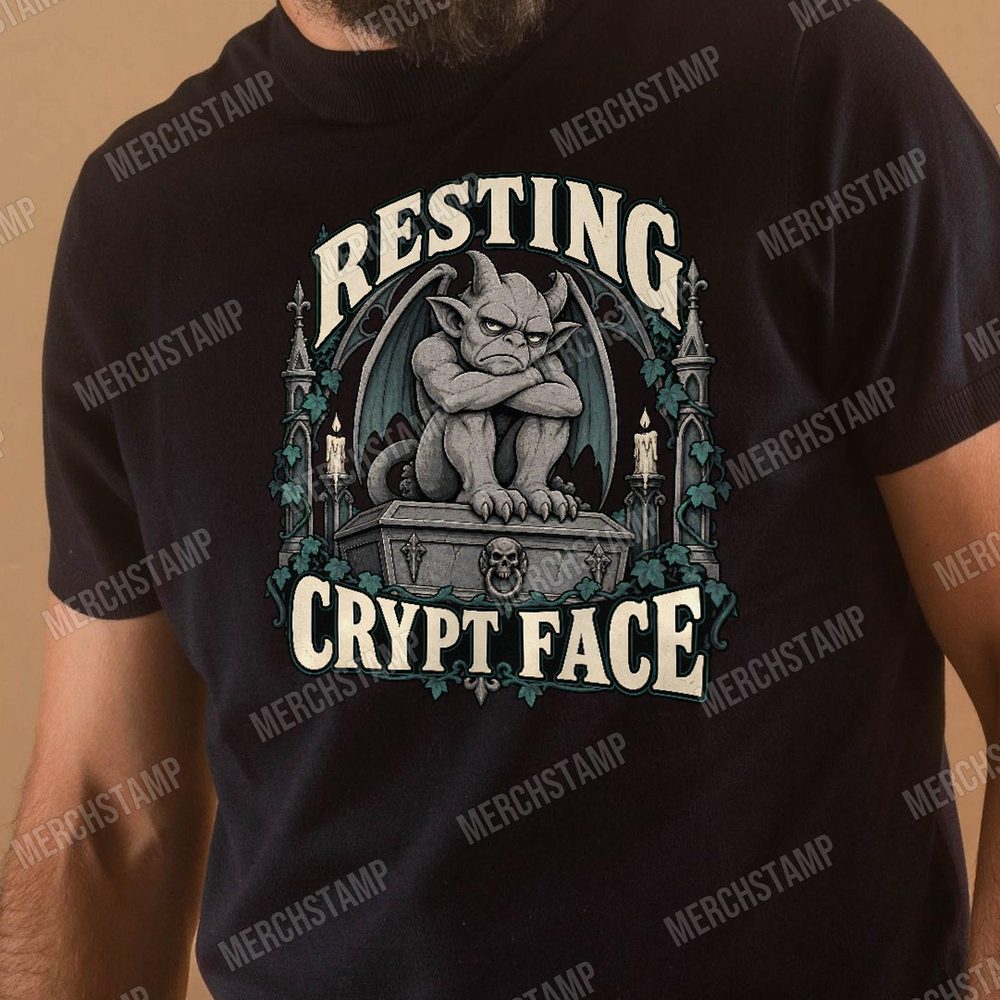Resting Crypt Face PNG design shown on a black t-shirt, a cross-armed stone gargoyle sitting on a coffin between gothic arches and candles above the words Resting Crypt Face
