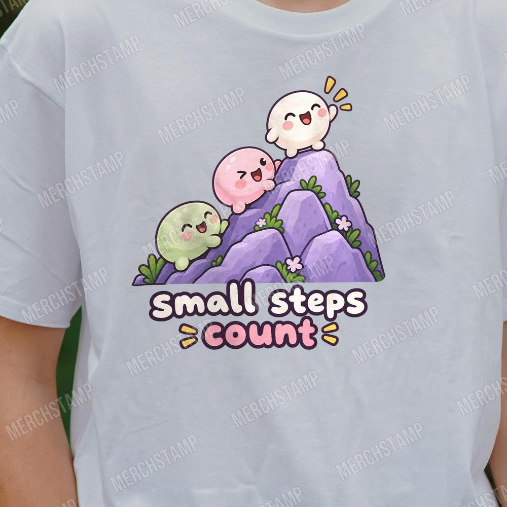 Small Steps Count PNG design shown on a light grey t-shirt, three round slime characters climbing a purple rocky mountain above the words small steps count
