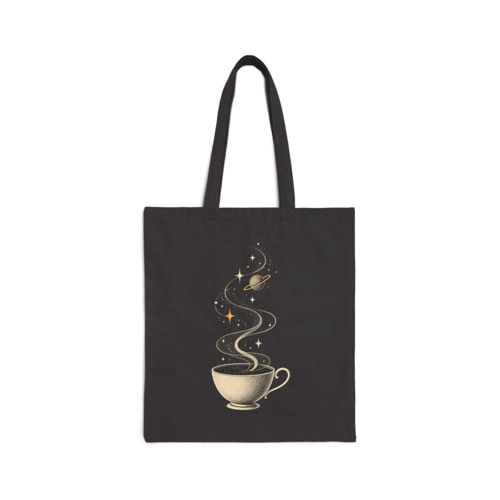Cosmic Teacup tote bag in black cotton canvas, printed with a white teacup whose steam curls up into stars and a small planet
